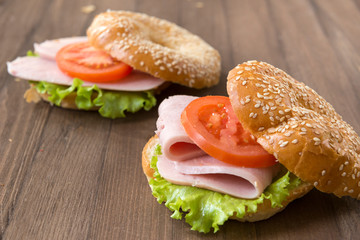 sandwich on a round bun with sesame seeds, 2 sandwiches with ham, tomato and lettuce