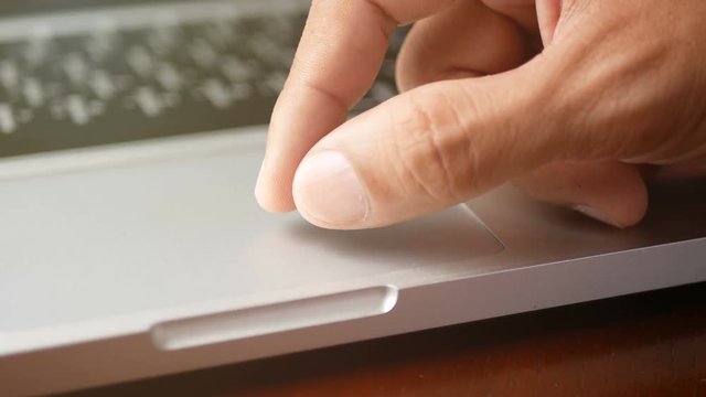 4K. close-up a man working with notebook laptop, using finger with keyboard and touchpad or trackpad for slide and zoom in, zoom out. 