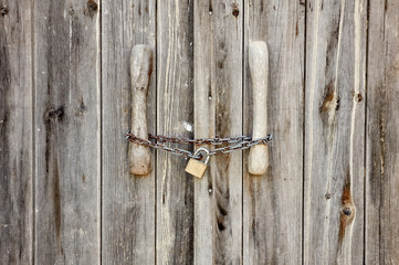 Old wooden door locked with rusty chain and padlock