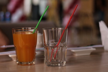 two glasses on the table. one empty, one with juice. catering