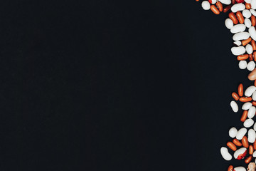background with space for text. View from above. multi-colored beans scattered on a black...