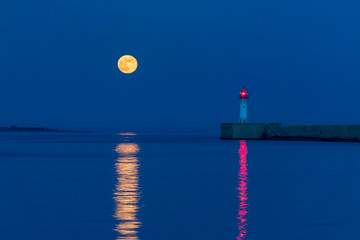 Luna llena iluminando la entrada al puerto de Almeria con el faro encendido y reflejandose en el agua © M. Perfectti