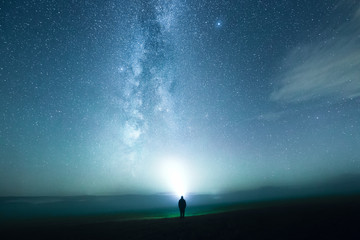 Junger Mann leuchtet die Milchstraße mit einer Taschenlampe an