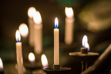 Many burning church wax yellow candles in large on a special stand