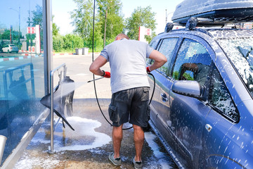 Man pours active foam car body. Car wash. Self-service washing complex. High pressure car wash.