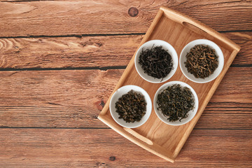 the white drinking bowls of assortment of dry tea in order on wooden background