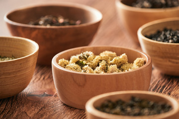 assortment of dry tea in white bowls on wooden surface