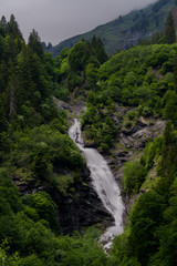 Fototapeta na wymiar vertical view of a high picturesque waterfall in lush green forest landscape