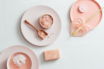 Top view of spa setting with salt, flower, soap on white background