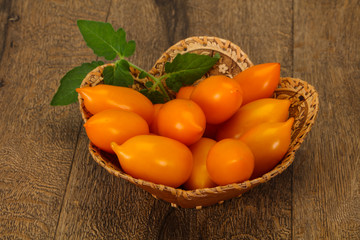 Yellow tomato heap in the wooden bowl