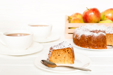 Morning still life with cake with icing served tea and raw apples on white table. Selected focus