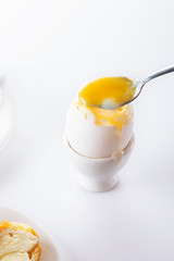 Soft boiled egg in egg cup on white background, plate and cup. Close up. Selective focus. High key.