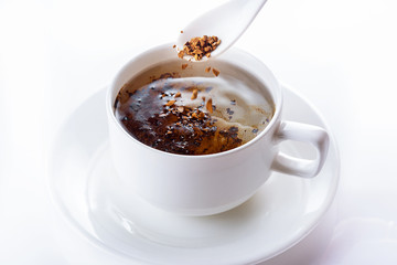 Instant coffee is filled in a cup with hot water. Close up. Selective focus. High key.