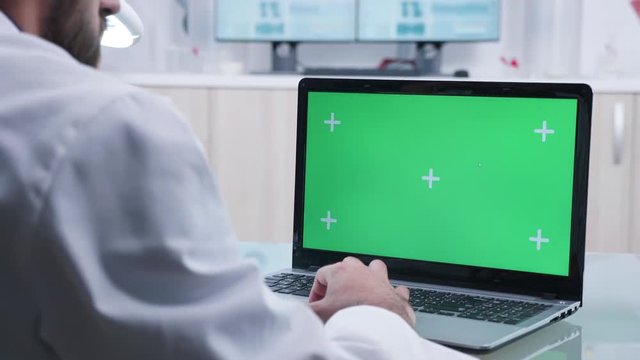 Doctor works on laptop with green screen in modern research laboratory
