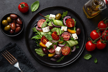 Fresh greek salad with tomato, cucumber, bel pepper , olives and feta cheese on black plate