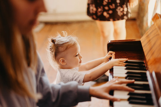 Cute little happy child girl playing piano in a light room. Selective focus, noise effect - Powered by Adobe