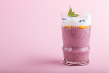 smoothie with honeysuckle, linen and chia in a glass on pink pastel background. side view.
