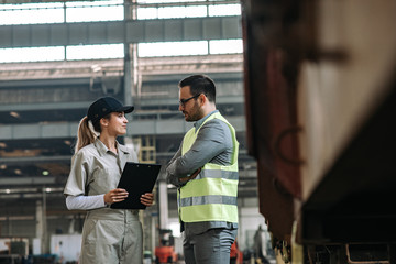 Contractor or manager talking to a female factory employee, side view.