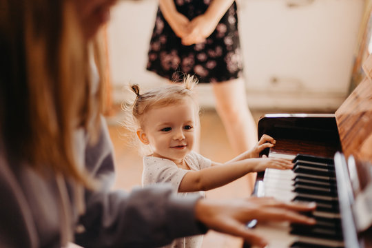 beautiful little girl with tails on head charismatic singing the song at the piano which plays mom. Selective focus, noise effect