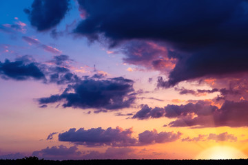 Evening sky at sunset background. Dark clouds hanging above horizon. Majestic cloudscape in blue,...
