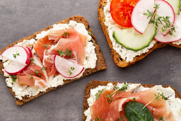 Sandwich with cereals bread and salami on dark marble background.