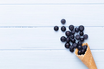 Fresh blueberries, in a heart shaped bowl on a wooden background.