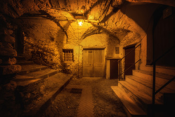 Fototapeta na wymiar Subterranean street in the night and cozy countryard in the old town of Dolceacqua, Liguria region, Italy