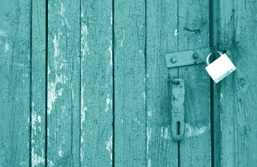 Old padlock on wooden gate in cyan tone.