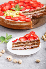 Homemade cake with yoghurt cream, strawberry and pistachio on a gray concrete  background. side view.
