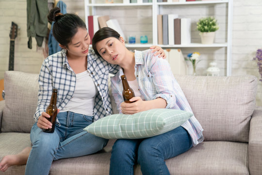 Young Sad Girl Talking With Her Best Friend About Problems. Upset Asian Woman Leaning On Sisters Shoulder Holding Beer Drinking Alcohol To Make Self Better. Lady Hug Consoling For Help And Support