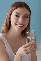 Smiling woman with glass of water indoors portrait