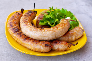 Grilled sausages in a plate with lettuce leaves