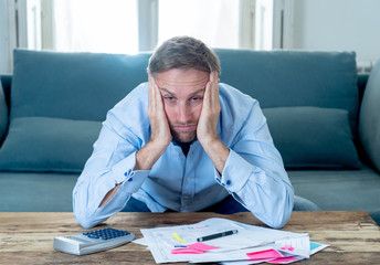 Upset man in stress paying bills counting finance with calculator bank papers expenses and payments