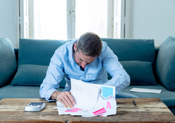 Upset man in stress paying bills counting finance with calculator bank papers expenses and payments