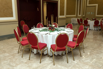 The wedding table setting is decorated with fresh flowers in a brass bowl and golden candles in brass candlesticks. Wedding floristry. Banquet table for guests. Bouquet with dahlias and eucalyptus