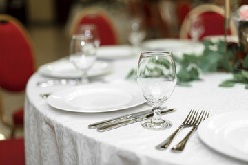 The wedding table setting is decorated with fresh flowers in a brass bowl and golden candles in brass candlesticks. Wedding floristry. Banquet table for guests. Bouquet with dahlias and eucalyptus
