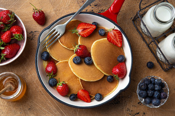 pancakes with fresh berry and honey in red pan for breakfast