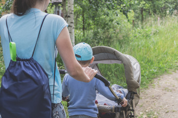 Young mother with a small child in a stroller resting in nature