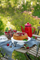 cake with fresh strawberry on wooden table in a garden