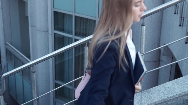 young business women in black jacket late and run on stair with notebook in hands