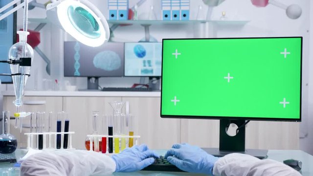 POV shot of scientist hands typing on computer with green screen chroma mock up in advanced laboratory