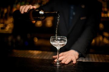 Bartender pours sparkling wine in a glass