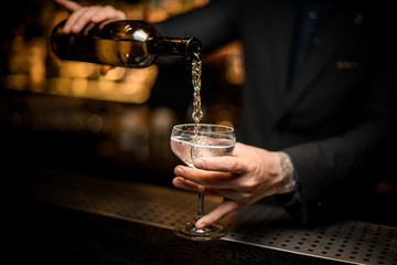 Fototapeta na wymiar Male bartender pouring champagne in a glass