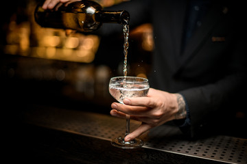 Male bartender pours champagne in a glass