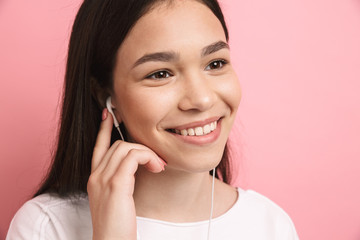 Portrait closeup of optimistic pretty girl wearing earphones smiling while listening to music