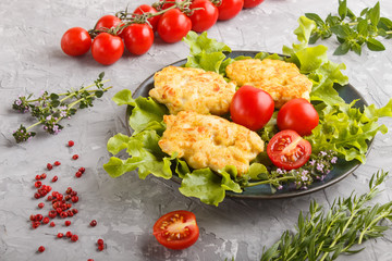 minced chicken cutlets with lettuce, tomatoes and herbs on a gray concrete background. side view.