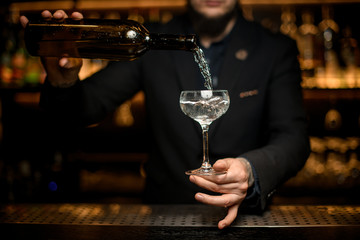 Bartender adds sparkling wine in a glass
