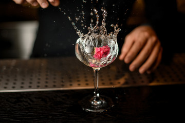 Bartender drops flower in an alcohol cocktail