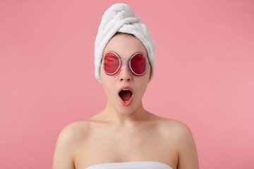Wow! Cool news! Young happy amazed girl after spa with a towel on her head and mask on eyes, with...