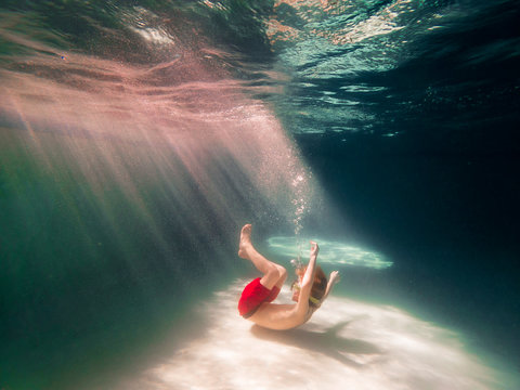 Boy curled up on the bottom of a swimming pool